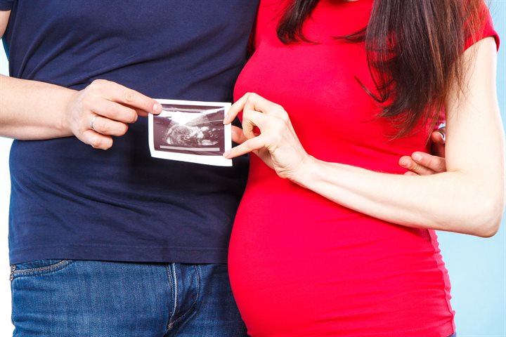 Man and pregnant woman holding a baby scan