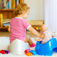 child sitting on potty with doll